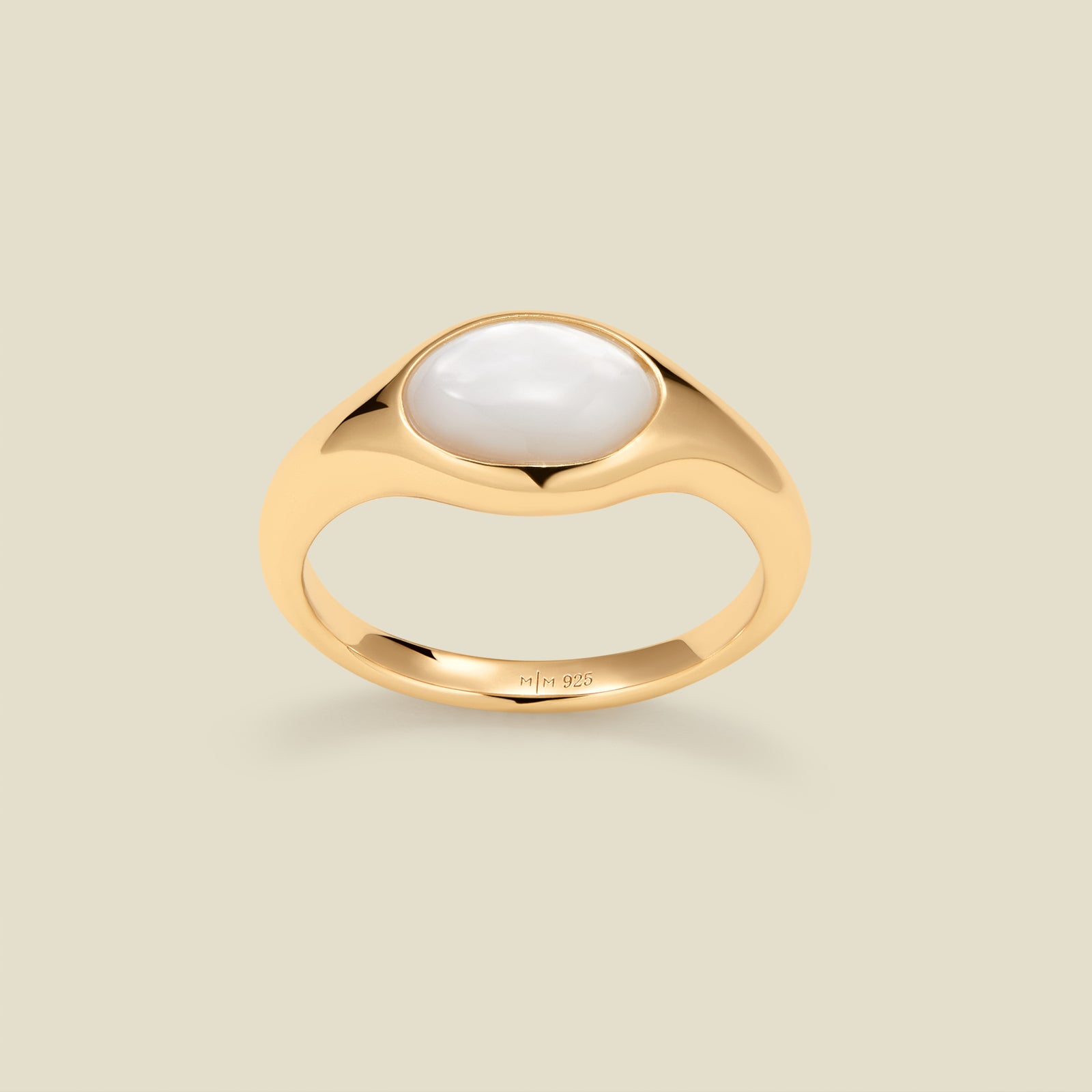 Gold ring with a bezel-set pearl stone against a neutral background.