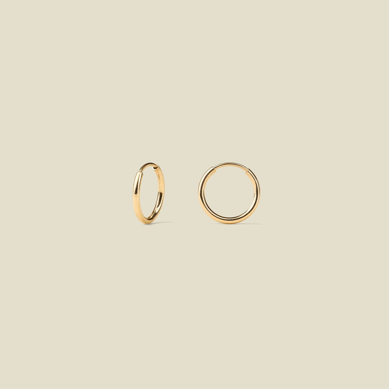 Gold hoop earrings on a beige background