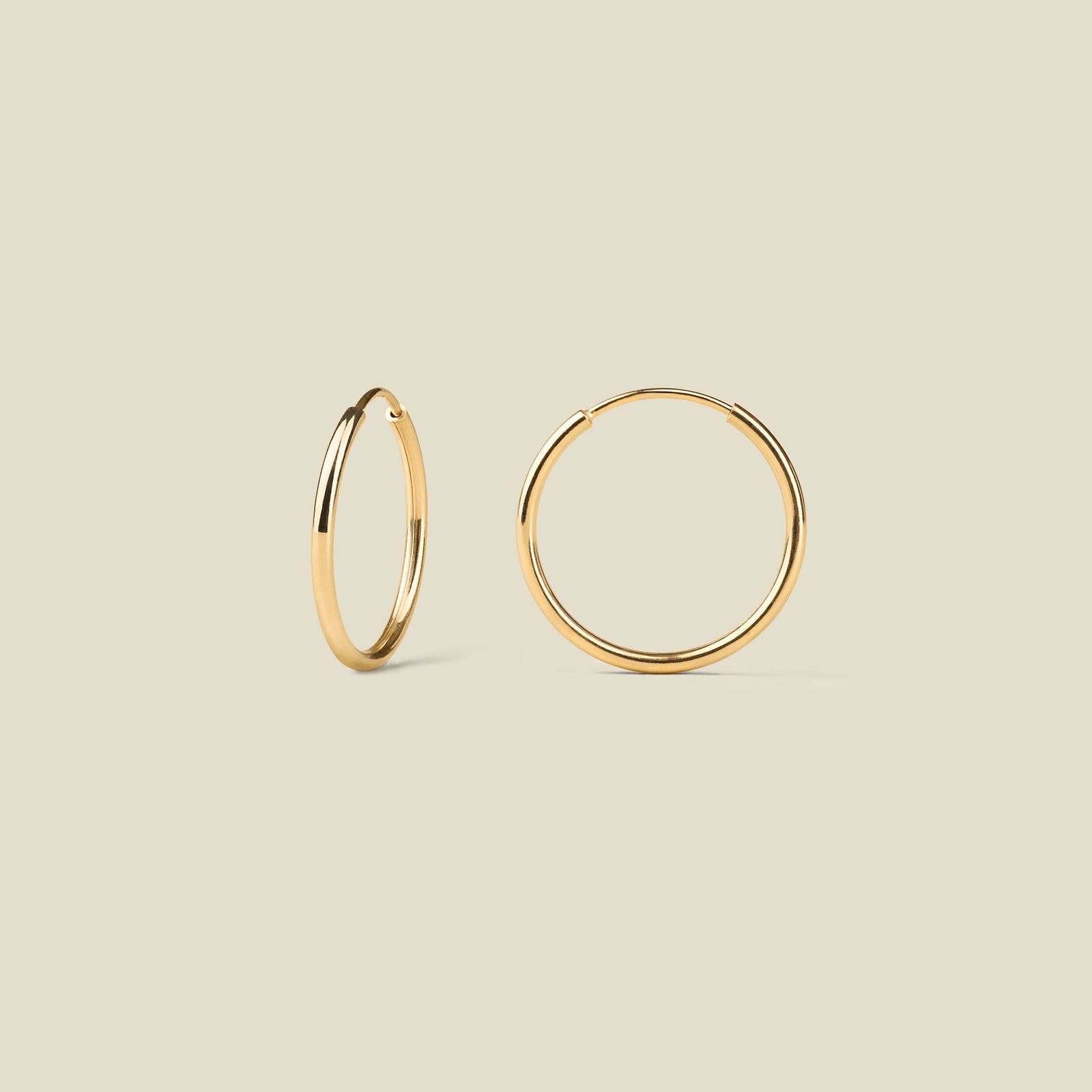 Gold hoop earrings on a beige background