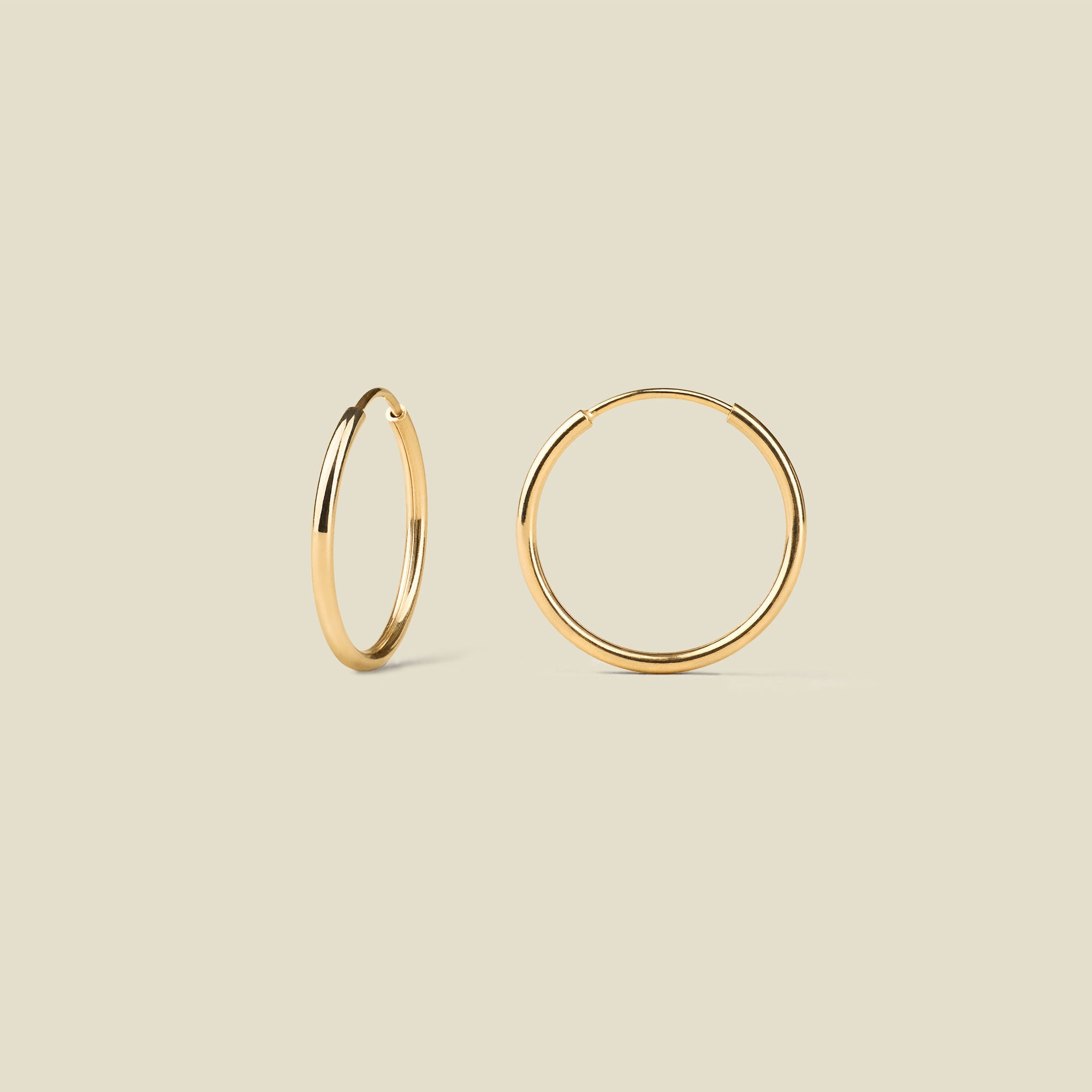 Gold hoop earrings on a beige background