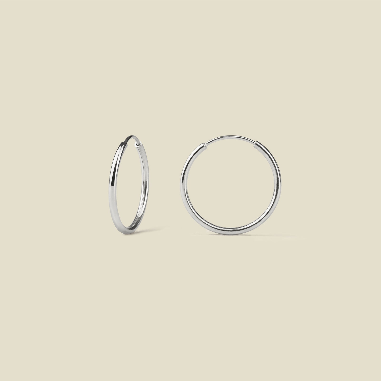 Pair of silver hoop earrings on a beige background