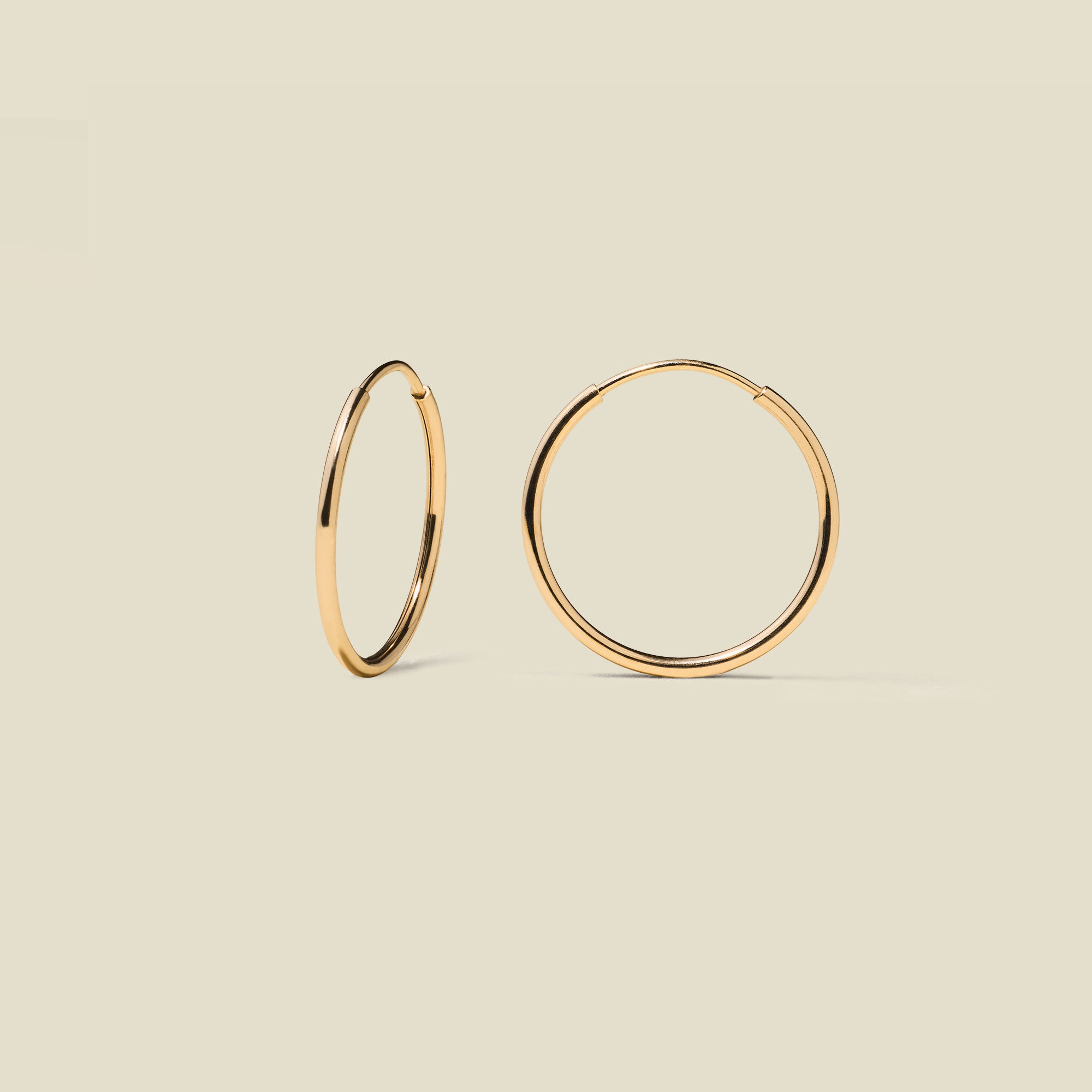 gold hoop earrings on a beige background