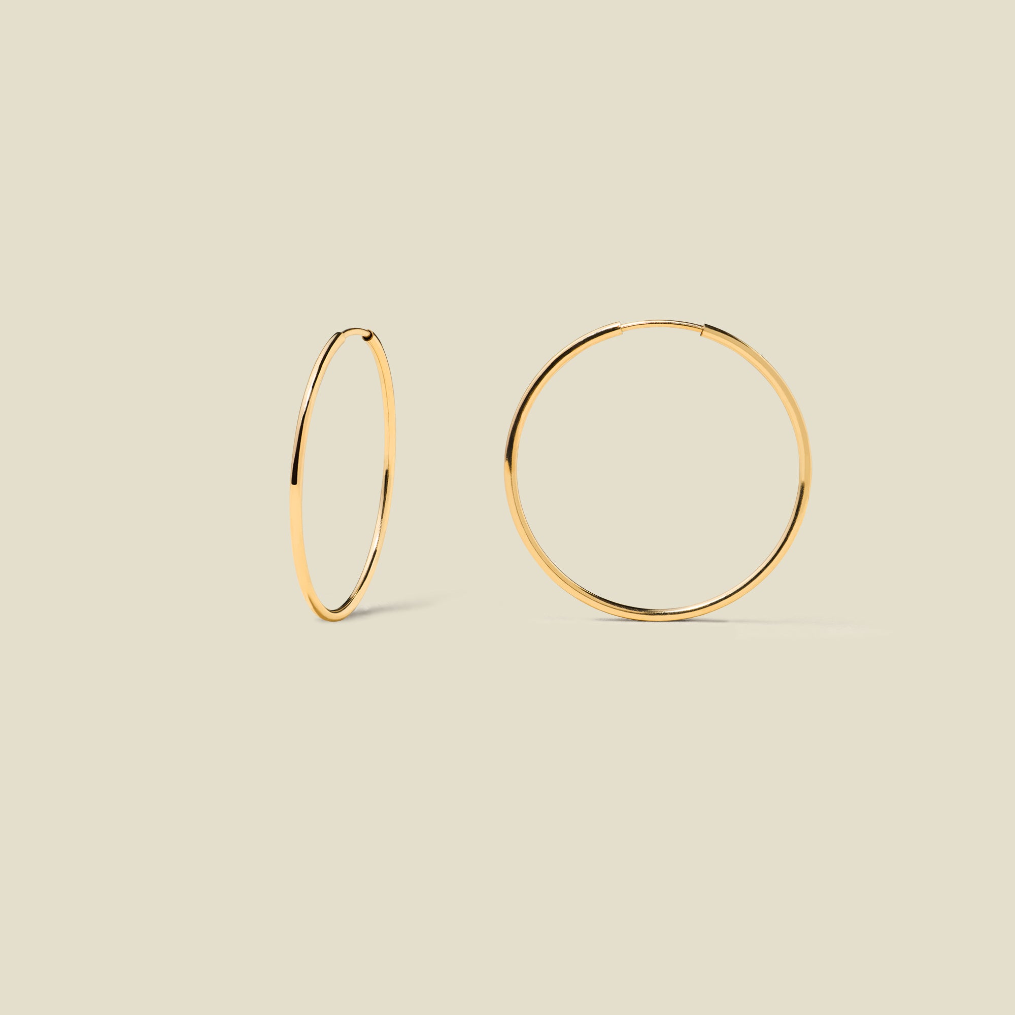 gold hoop earrings on a beige background