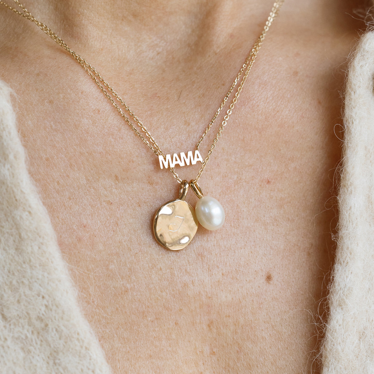 Gold “MAMA” necklace layered with gold disc charm and pearl pendant on model