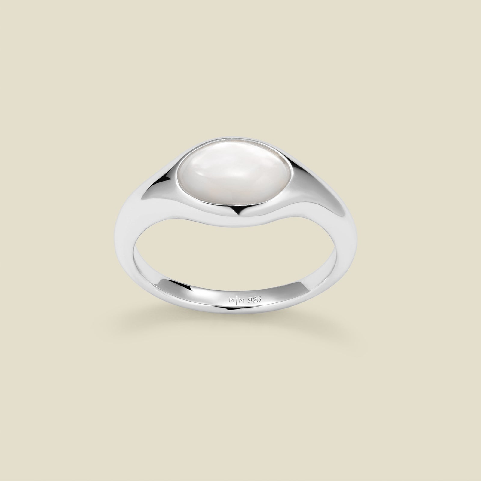 Silver ring with a bezel-set pearl stone against a neutral background.