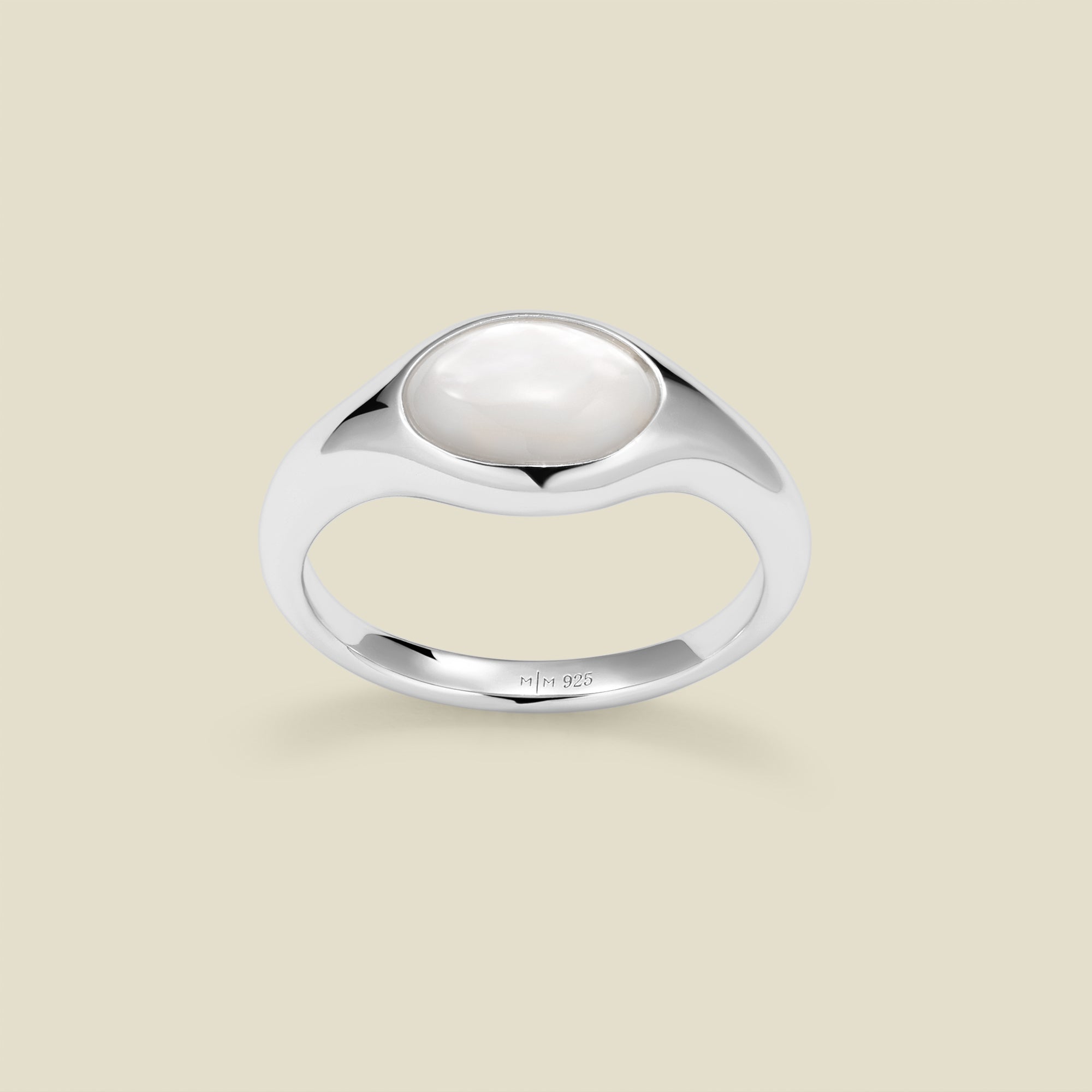 Silver ring with a bezel-set pearl stone against a neutral background.