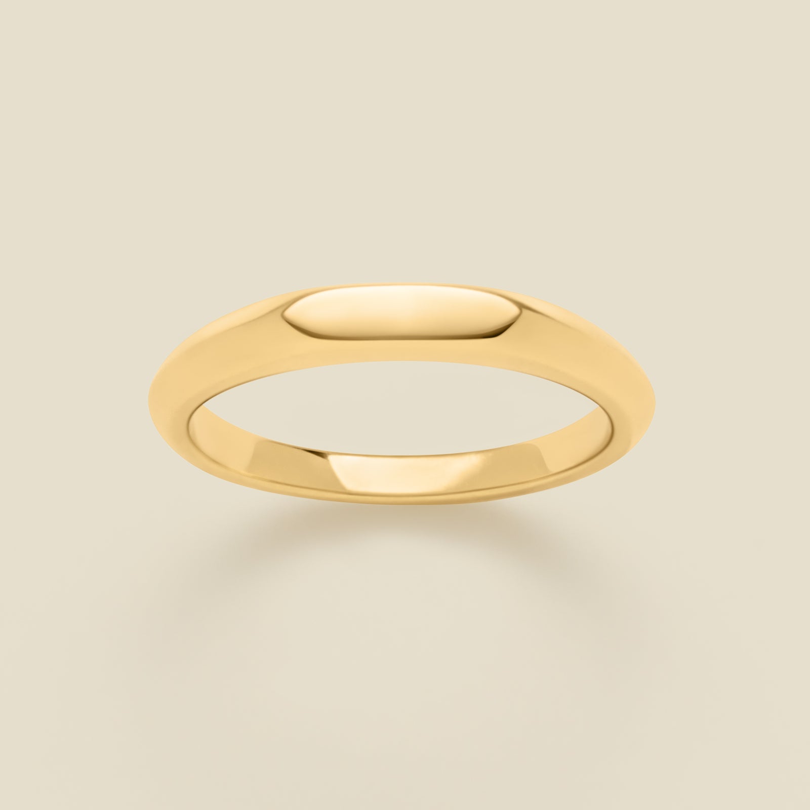 Gold signet ring on a beige background