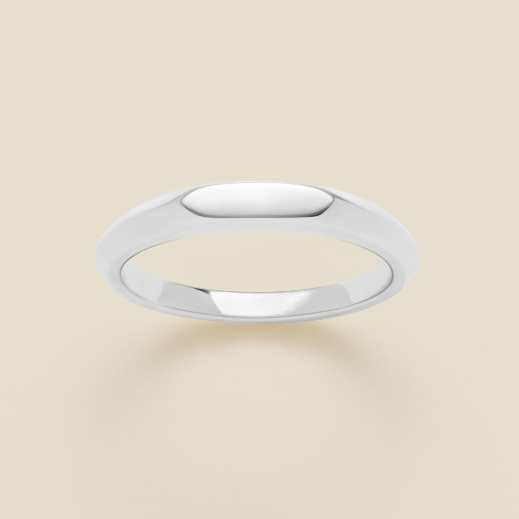 Silver signet ring on a beige background
