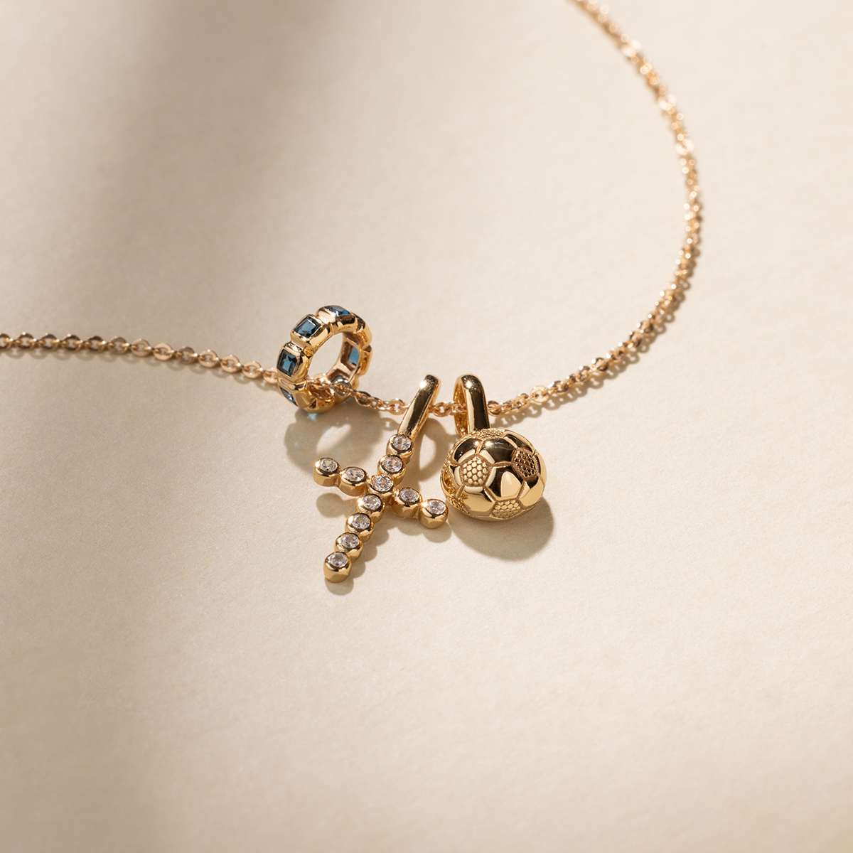 Gold necklace with three pendants on a beige background